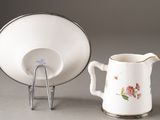 a small pitcher and a small cup on a stand