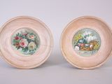 two plates with flowers painted on them sitting next to each other