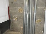 une camionnette blanche garée dans un garage, à côté d'un tas de tuyaux