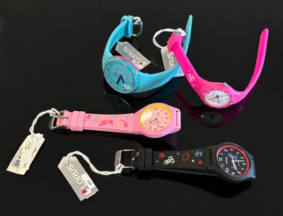 trois montres-bracelets, avec leurs étiquettes encore attachées, posées sur une table