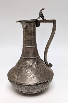an old silver pitcher with a handle on a white background