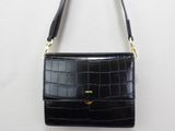 the small black purse is hanging on a white wall