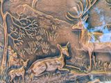 a metal plaque with a picture of a deer and other animals