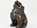 a bronze statue of a lion sitting on its hind legs