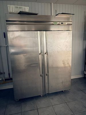 un grand réfrigérateur en acier inoxydable dans une cuisine au sol carrelé
