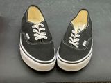 pair of black and white vans sneakers with white laces on a black surface