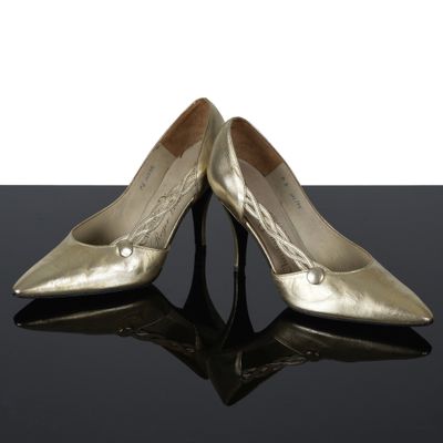 une paire de chaussures dorées posées sur une surface noire, sur fond blanc