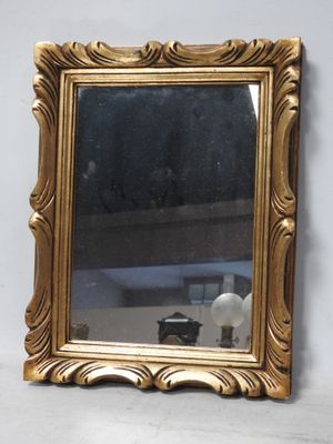 un miroir avec un cadre doré sur un mur blanc