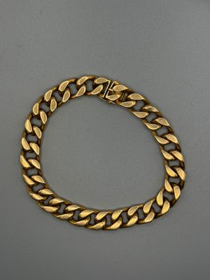 un bracelet en or avec des maillons de type « curb » sur fond gris