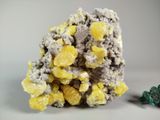 some yellow and green crystals are sitting on a white surface