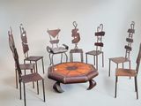 Plusieurs chaises et une table sont disposées en cercle sur un fond blanc.