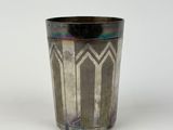 a silver cup with a design on it on a white surface