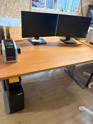 a desk with two computer monitors and a printer on it