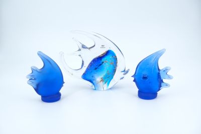 trois figurines de poissons en verre bleu posées sur une surface blanche