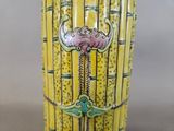 a yellow vase that has a pink flower on it