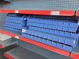 des rayons vides dans un magasin, sur lesquels sont posés des bacs bleus