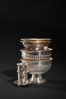 a group of silver dishes and cups sitting on top of a table
