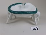 a small white bowl with a green handle on a table