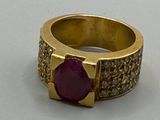 bague en or jaune sertie d'une pierre rouge entourée de diamants blancs
