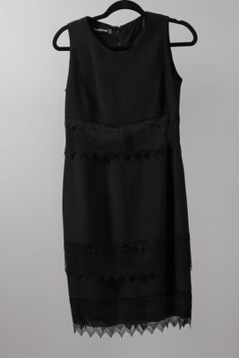 a black dress hanging on a hanger against a white wall