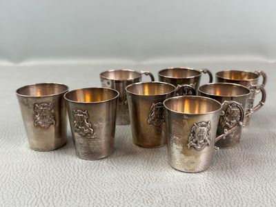 six silverplated cups with handles and handles on a white surface