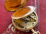 une montre de poche en or posée sur un livre rouge