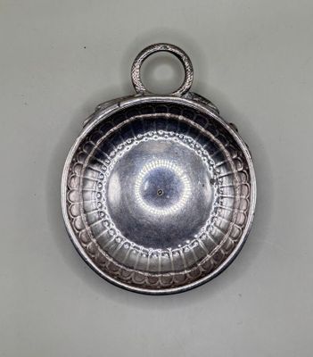 a silver plate with a circular design hanging on a wall