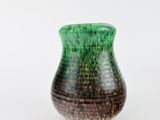 a green and brown vase sitting on a white surface