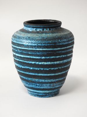 un vase bleu et noir posé sur une surface blanche