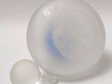 a glass vase with a ball inside of it on a white surface