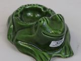 a green frog sitting on top of a white table