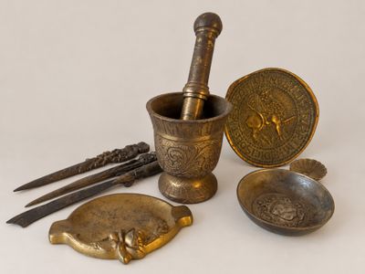 an assortment of brass objects including a mortar, spoon, and other items