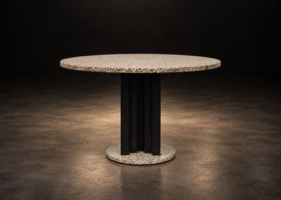 une table à manger ronde avec un piètement noir et un plateau en marbre blanc