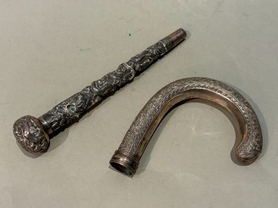une canne en argent et un pommeau de canne en argent posés sur une table