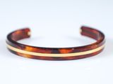 un bracelet en écaille de tortue avec des rayures dorées sur fond blanc