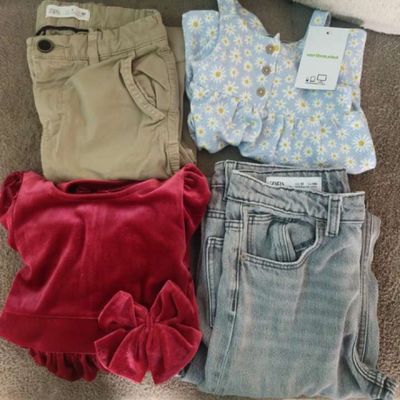 three pairs of baby clothes are laid out on the floor