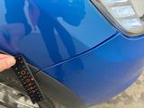 a person holding a measuring tape on a car ' s bumper