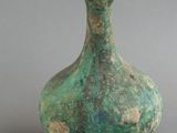 un vase vert avec une poire à côté