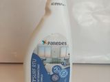 une bouteille de produit nettoyant posée sur un plan de travail, à côté d'un micro-ondes