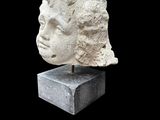 an image of a stone head on a stand against a black background