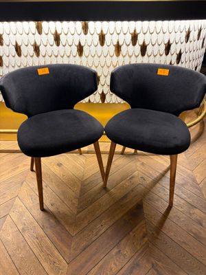 two black chairs with wooden legs sitting on a wooden floor