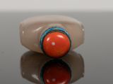 a close up of a ring with a red bead on it