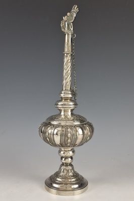 un vase en argent surmonté d'un oiseau, posé sur une table
