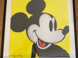 framed mickey mouse art print in a black frame on a wooden floor