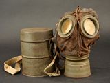 a gas mask sitting next to a canister on a table