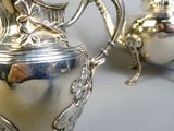 a silver tea pot sitting on a table next to a silver tea pot