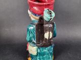 a ceramic figurine of a man with a bucket on his head
