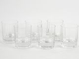 six verres transparents sont alignés sur une surface blanche