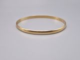 a gold bang bracelet on a white background