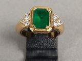 gros plan d'une bague avec une pierre verte entourée de diamants blancs